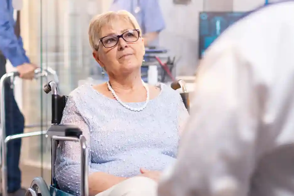 Patientin im Rollstuhl im Gespräch mit medizinischem Personal